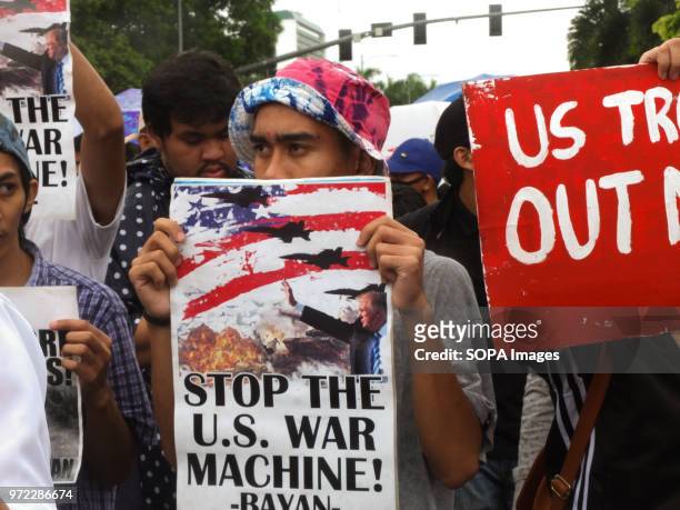 Male protester holding a placard saying stop the U.S. War machine. While the Philippines celebrated it's 120th Independence Day, militant groups...
