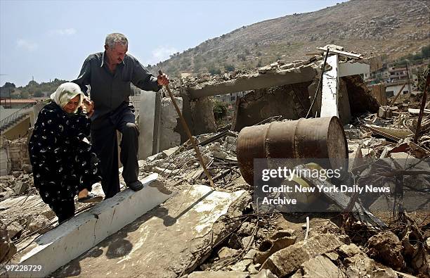 An old man and woman climb over rubble in Aitaroun, Lebanon, only a few miles from the border with Israel, as they flee their village after spending...