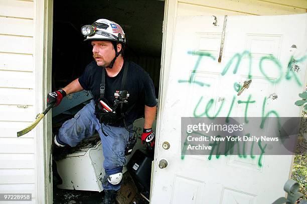 An Urban Search and Rescue worker searches a home for survivors of Hurricane Katrina in Waveland, Miss. Message scrawled on the door reads "I'm OK -...