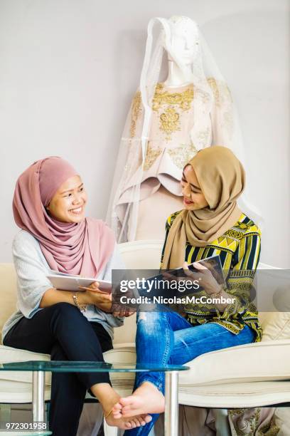 muslim wedding dress designer smiling over collection catalog with customer - wedding vendor stock pictures, royalty-free photos & images