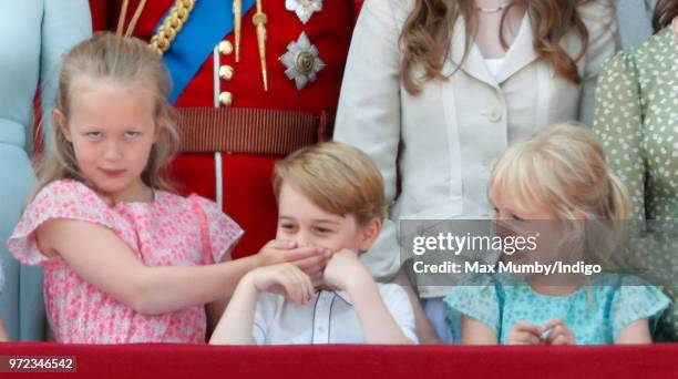 Savannah Phillips puts her hand over Prince George of Cambridge's mouth as they and Isla Phillips stand on the balcony of Buckingham Palace during...