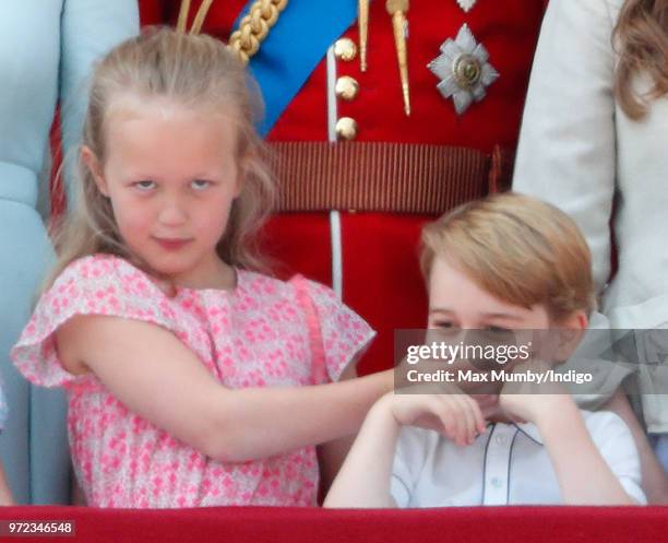 Savannah Phillips puts her hand over Prince George of Cambridge's mouth as they stand on the balcony of Buckingham Palace during Trooping The Colour...