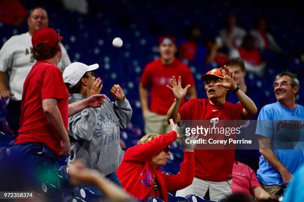 Fans try to each a foul ball between the Philadelphia Phillies and the Milwaukee Brewers during the ninth inning at Citizens Bank Park on June 8,...