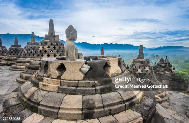 a buddha statue with the hand position of dharmachakra mudra in an opened perforated stupa on the circular top terrace of 9th century borobudur buddhist temple, central java, indonesia - dharmachakra stock pictures, royalty-free photos & images