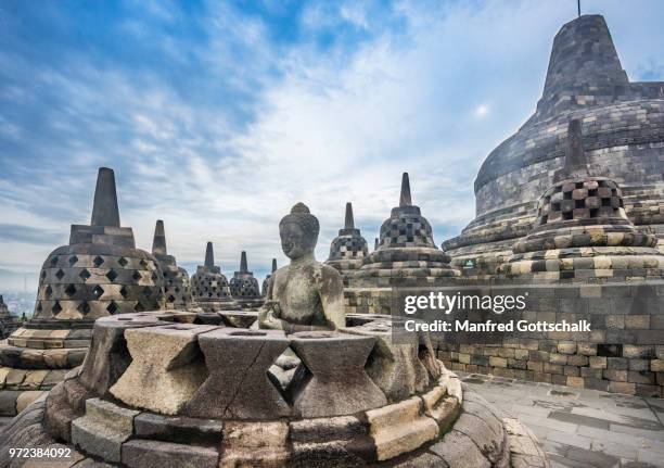 buddha statue with the hand position of dharmachakra mudra in an opened perforated stupa on the circular top terrace of 9th century borobudur buddhist temple, central java, indonesia - dharmachakra stock pictures, royalty-free photos & images