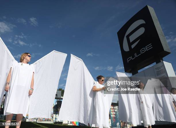 People dressed as angels stand in front of the memorial set up for the shooting victims at Pulse nightclub where the shootings took place two years...