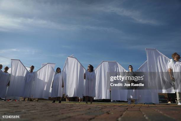 People dressed as angels stand in front of the memorial set up for the shooting victims at Pulse nightclub where the shootings took place two years...