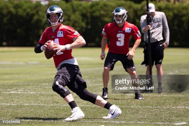 Carson Wentz of the Philadelphia Eagles looks to pass the ball as Joe Callahan looks on during Eagles minicamp at the NovaCare Complex on June 12,...