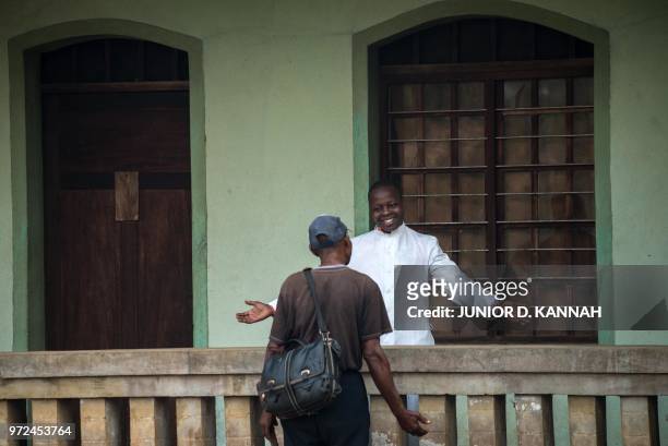 Father Lucien Ambunga, a Catholic priest who survived the Ebola virus, welcomes a faithful at the St Joseph Church in Itipo on June 11, 2018. - The...