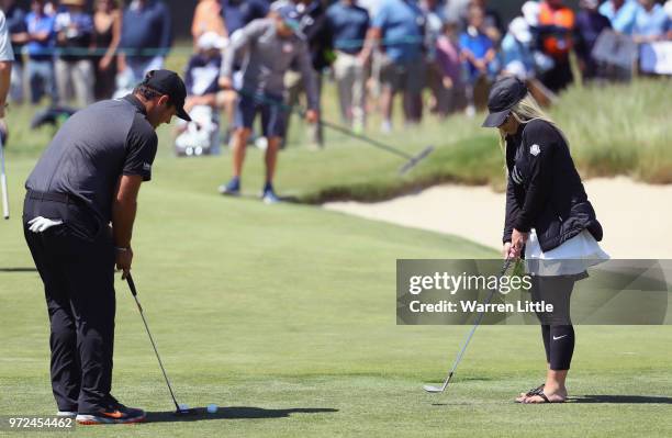 Patrick Reed of the United States putts as his wife Justine Karain looks on during a practice round prior to the 2018 U.S. Open at Shinnecock Hills...