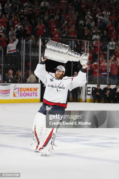 Washington Capitals goalie Braden Holtby victorious, holding up Stanley Cup over his head after winning game and series vs Vegas Golden Knights at...