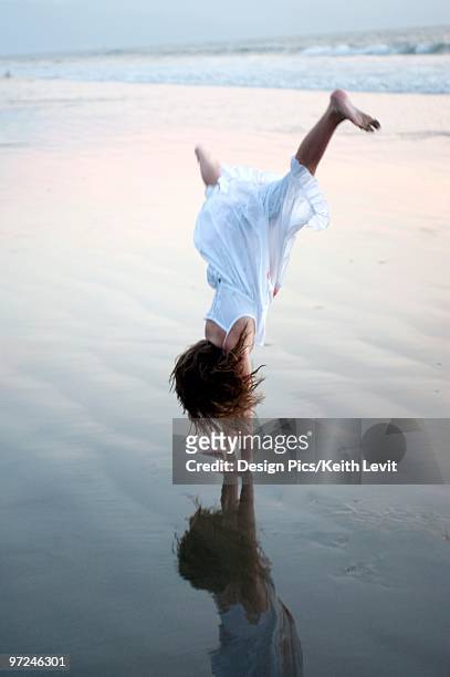 girl doing a cartwheel on the beach - girl in dress doing handstand stockfoto's en -beelden