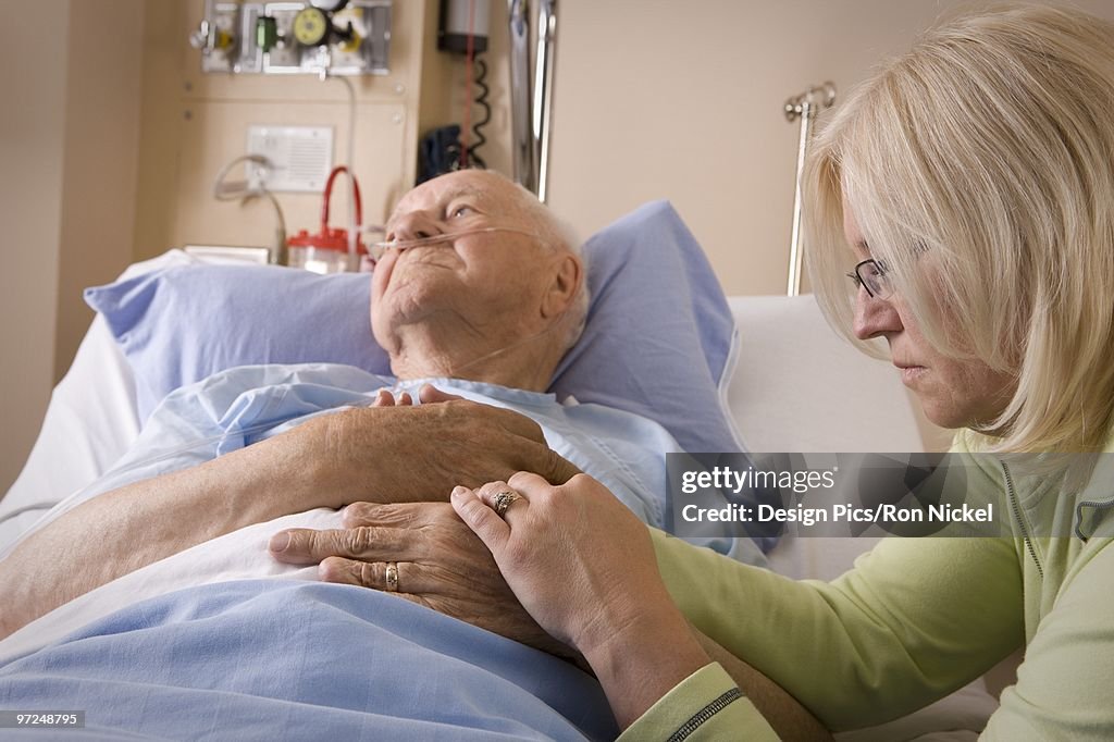 Woman sitting by a man's hospital bed