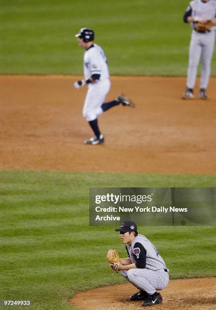 Arizona Diamondbacks' closer Byung-Hyun Kim sits stunned on the mound as Scott Brosius rounds the bases after hitting a game-tying homer in the ninth...