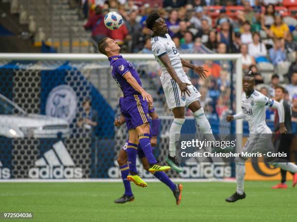 Will Johnson of Orlando City and Alphonso Davies of the Vancouver Whitecaps fight for the ball during a match between Orlando City SC and Vancouver...