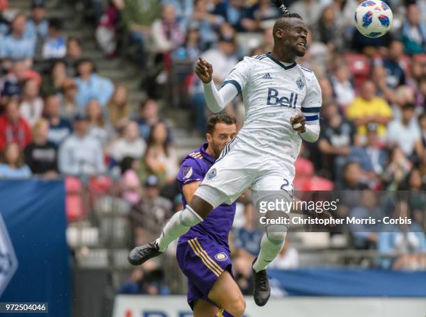 Kei Kamara of the Vancouver Whitecaps heads the ball in front of RJ Allen of Orlando City during a match between Orlando City SC and Vancouver...