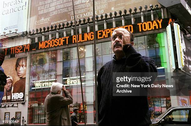Anxious pedestrians watch for bulletins outside the Nasdaq Building in Times Square. Microsoft stocks - and the Nasdaq average - was already plunging...