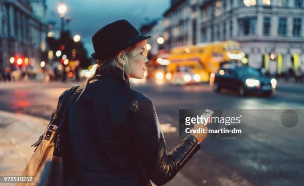 frau in london in der nacht warten auf ein taxi - taxi fahrgemeinschaft stock-fotos und bilder