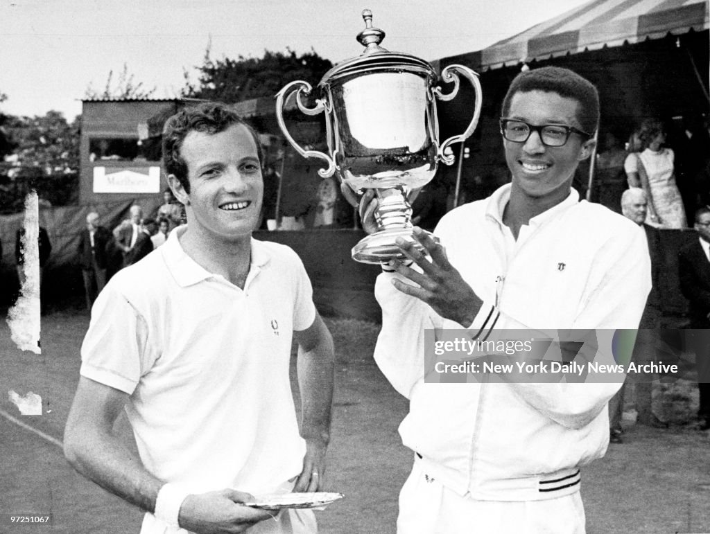 Arthur Ashe holds trophy after defeating Tom Okker (left), o