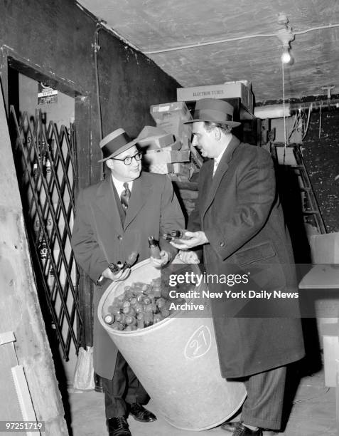 Assistant District Attorneys Al Blinder and Fred Barone inspect a barrel of defective TV tudes found in the basement at 40 Featherbed Lane, Bronx.