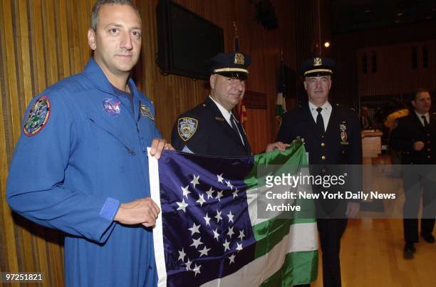 Astronaut Mike Massimino holds a NYPD flag with Sgt. Jack Vaccaro and Deputy Inspector Bill Callahan at One Police Plaza. Massimino handed over the...