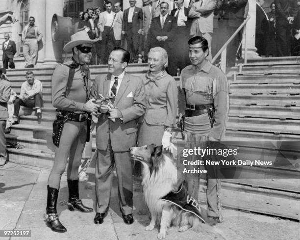 At the steps of City Hall, the Lone Ranger, Mayor and Mrs. Wagner, Tonto and Lassie, look over guns that shoot only silver bullets.