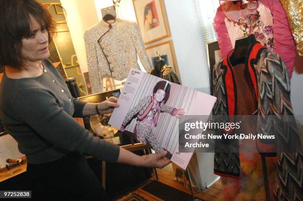 Auction coordinator Carolyn Salter shows outfits worn by the Jackson family, while holding a photo of a young Michael Jackson, as they're previewed...