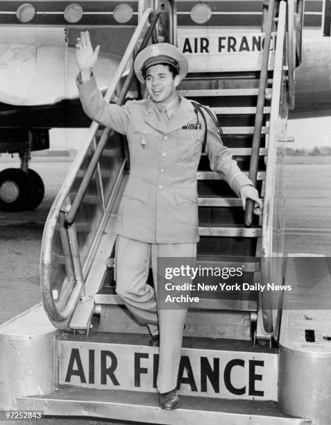 Audie Murphy, America's "most decorated soldier", waves to crowds while descending the steps of an Air France plane.