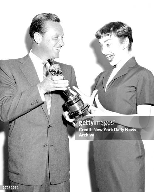 Audrey Hepburn, winner of the 1953 Academy Award for her performance in "Roman Holiday," is delighted to get the Oscar from William Holden, another...