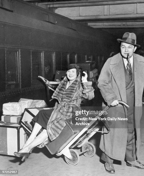 Edward G. Robinson gives Marilyn Miller and luggage a lift on hand cart at Grand Central Terminal.