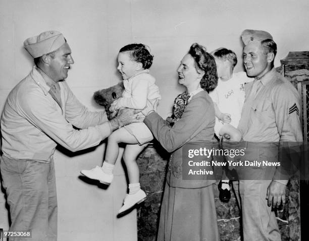 Australian war bride, Edna Mayerhofer, giving Corporal Daniel J. Sprague his son, Daniel Jr., as Sgt. Howard Mayerhofer holds his son, Stephen.