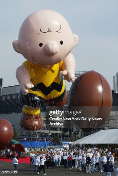 Handlers keep a tight rein on Charlie Brown and his football as balloons are tested out in the parking lot at Giants Stadium in preparation for...