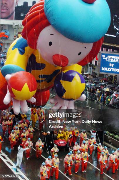 Handlers maneuver the Macy's clown balloon through Times Square during the 80th annual Macy's Thanksgiving Day Parade. Despite gusty winds and...