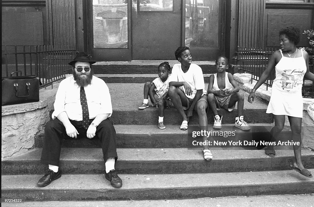 Hasidic man and black children share a stoop in Crown Height