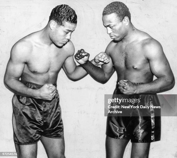 Heavyweight champ Joe Louis and challenger John Henry Lewis make fists at one another following weigh-in yesterday. Joe scaled quarter of a pound...