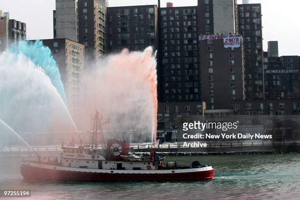 Fire boat sprays colored water as members of two volunteer fire companies unfurl huge get-well-soon banners from a rooftop on Roosevelt Island for...