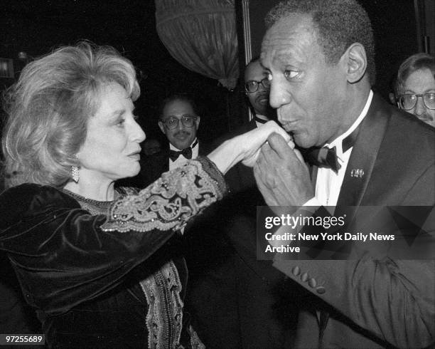 Barbara Walters is greeted by Bill Cosby at cocktail party.
