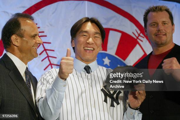 Hideki Matsui, the newest New York Yankee, gives the thumbs-up sign as manager Joe Torre and pitcher Roger Clemens look on at the Marriott Marquis in...