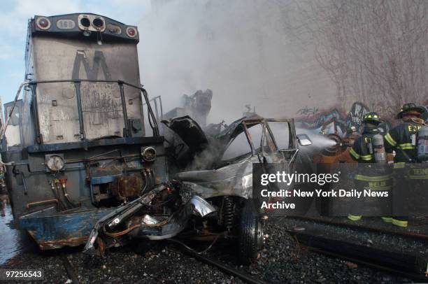 Firefighters play a hose on the wreckage of a truck after it was hit by a runaway locomotive in Maspeth, Queens. An unmanned locomotive broke loose...