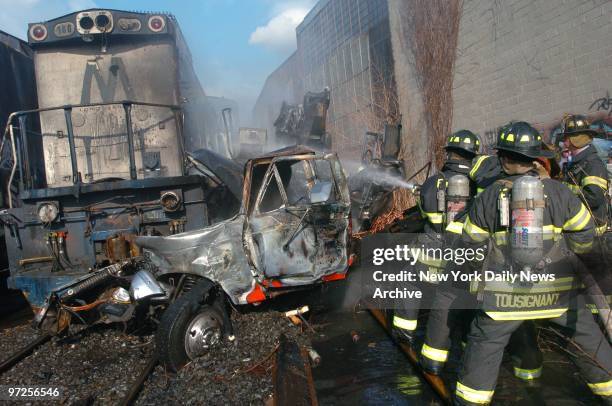 Firefighters play a hose on the wreckage of a truck after it was hit by a runaway locomotive in Maspeth, Queens. An unmanned locomotive broke loose...