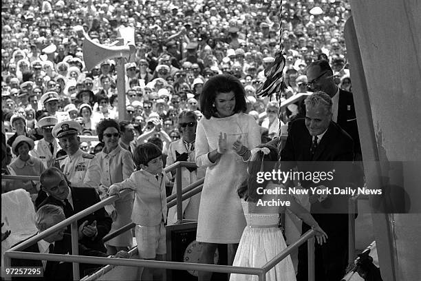 Jacqueline Kennedy applauds daughter Caroline as son John Jr. Looks on at launching of the carrier John F. Kennedy.