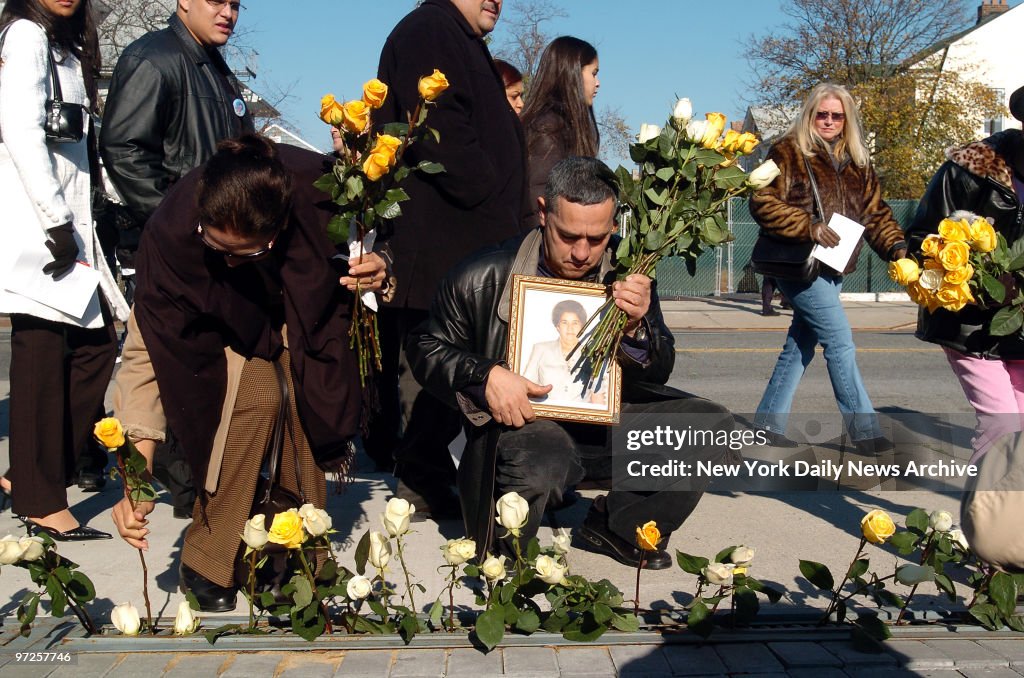 Family members and friends place roses along the sidewalk in