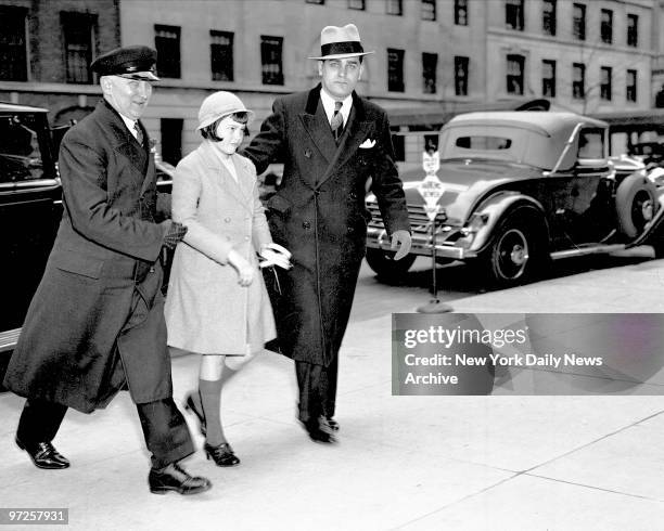 Holding her palm and assisted by chauffeur, little Gloria Vanderbilt returns to mother's home after attending Palm Sunday services at Church of St...