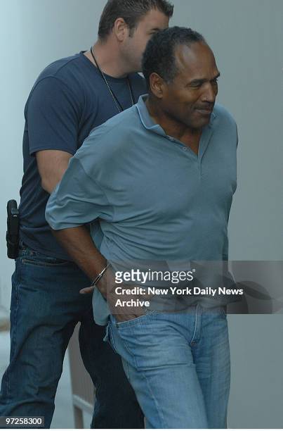 In handcuffs, O.J. Simpson is transferred by police officers to the Clark County Detention Center in Las Vegas, Nev., after being arrested in...