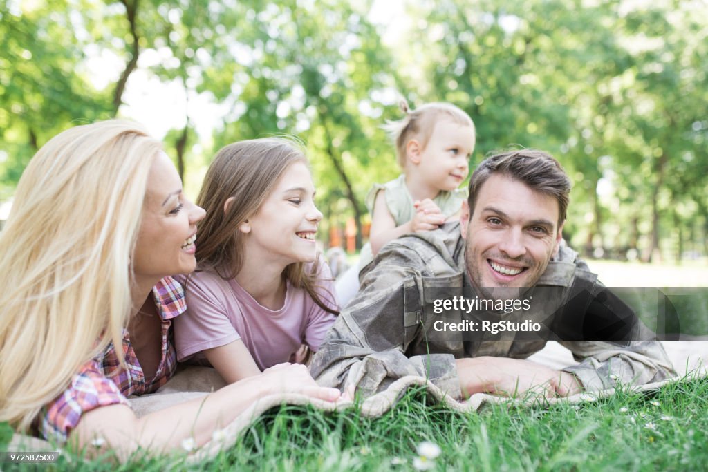 Soldier lying down on a blanket outdoors with his family