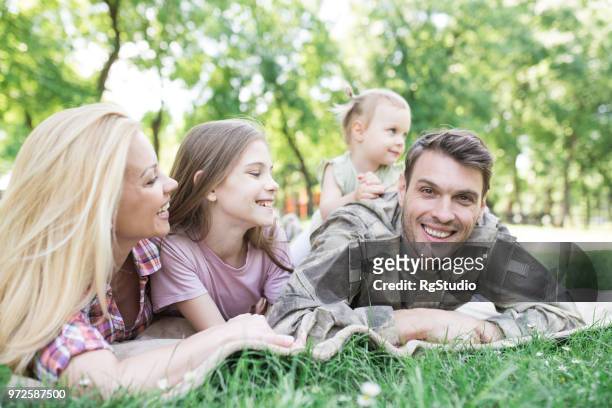 soldier lying down on a blanket outdoors with his family - resident stock pictures, royalty-free photos & images