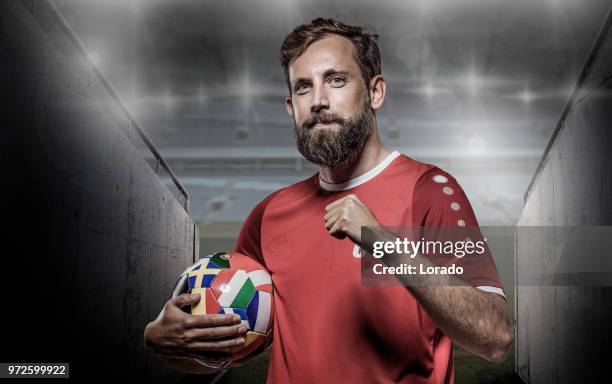 bearded caucasian football player holding a soccer ball in front of stadium lights - team captain stock pictures, royalty-free photos & images