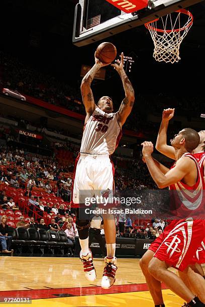 Michael Beasley of the Miami Heat goes up for a shot against Shane Battier of the Houston Rockets during the game at American Airlines Arena on...