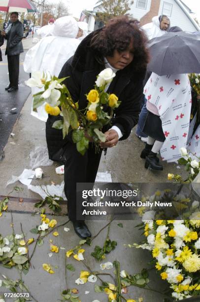 Family members scatter yellow and white flowers in remembrance of their loved ones during a rainy memorial service at Newport Ave. And Beach 131st...