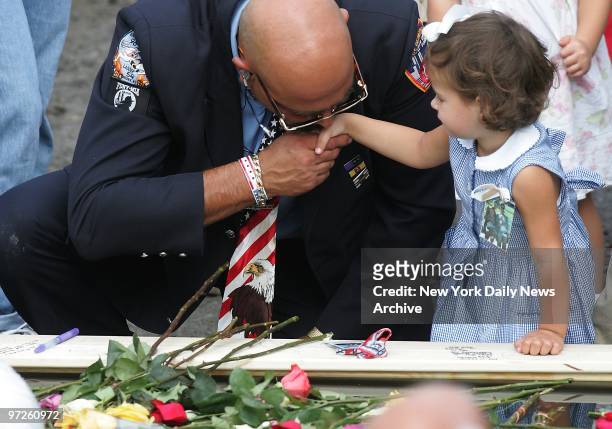 Firefighter kisses hand of a little girl as they stand over a reflecting pool during ceremonies at Ground Zero this morning commemorating the third...